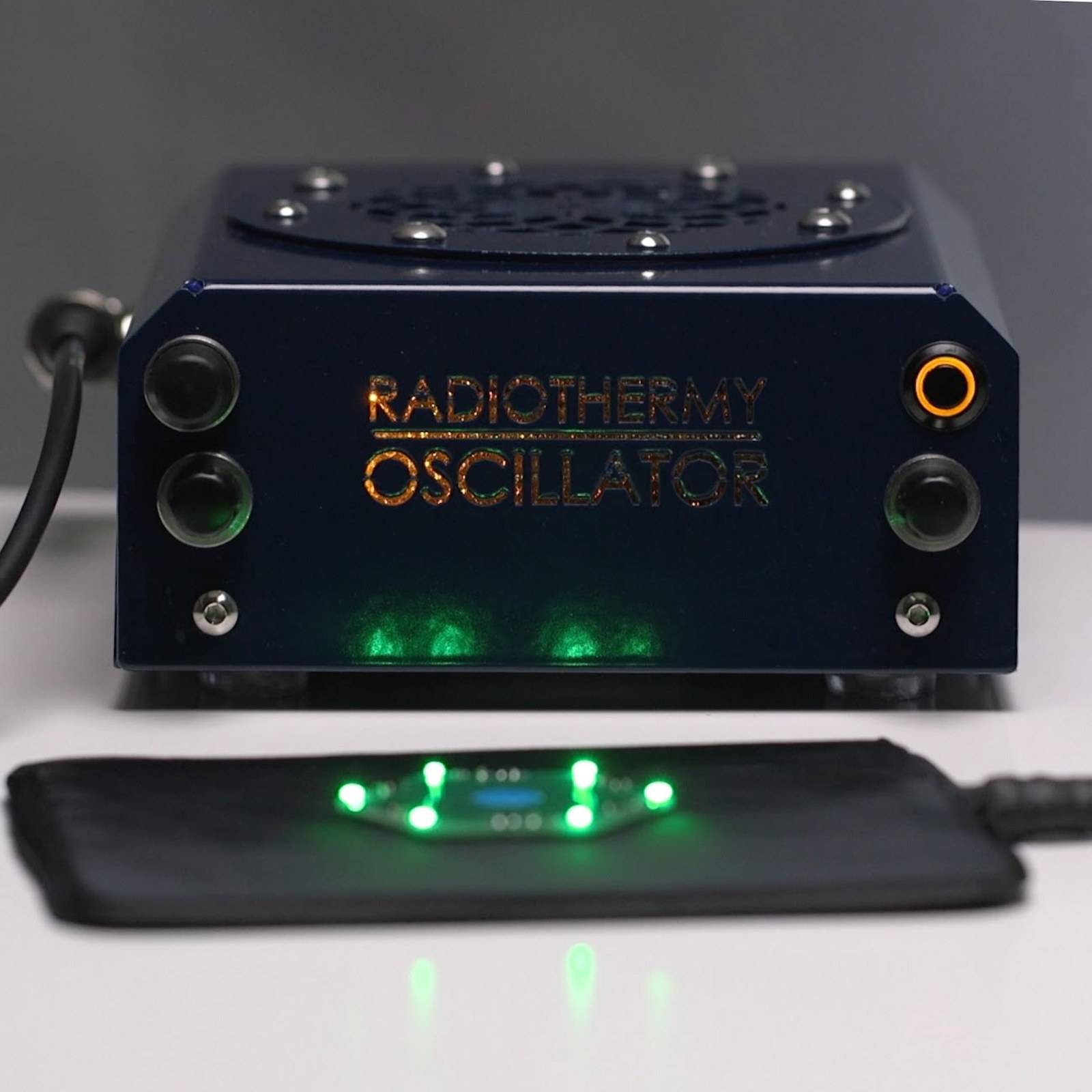 Radiothermie-Oszillator mit angeschlossenem RadioMat A6 Applikator-Pad, auf dem eine LED-Platine grün leuchtet